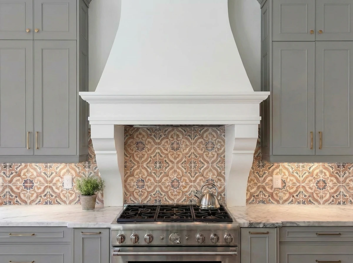 White cast stone tapered range hood with corbels over a patterned tile backsplash